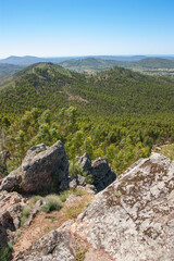 View over green central Portugal on a sunny day with a blue sky from a mountain in Vila de Rei with granite stone boulder blocks in the foreground.