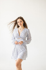 Naklejka premium beautiful woman model posing in white polka dot dress in studio