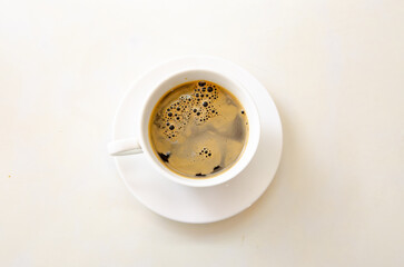 White cup and black coffee on white table in top view