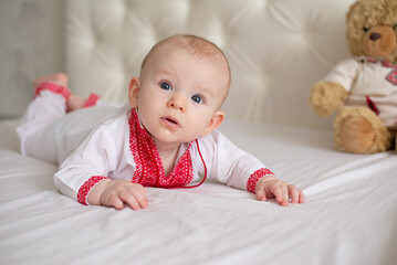 newborn baby boy lying on bed in Ukrainian embroidery at home surprised thoughtful