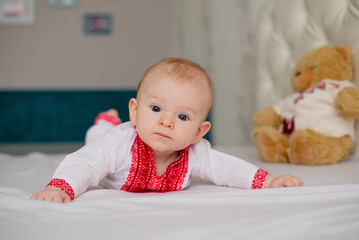 newborn baby boy lying on bed in Ukrainian embroidery at home surprised thoughtful