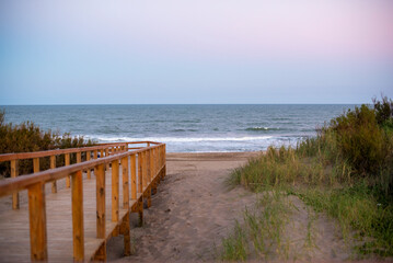 Wooden boardwalk leading to a serene beach at dusk