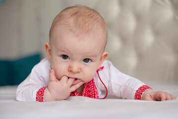 newborn beautiful baby boy lying on bed in Ukrainian embroidery with smile