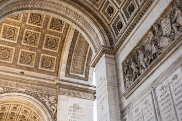 Visitors admire the impressive architecture of the Arc de Triomphe under clear blue skies in Paris 