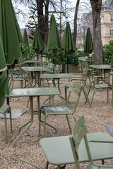 Outdoor seating area with green umbrellas and tables in a park during early spring