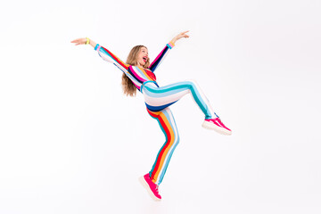 A young woman with long blond hair joyfully dancing in a vibrant striped jumpsuit against a white...
