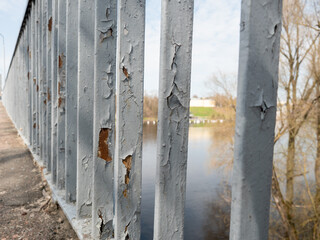 Rusty iron fence on the bank of the river in the spring