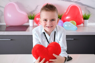 Charming, joyful, smiling boy with heart-shaped toy in his hands for Valentine's Day. Concept of...
