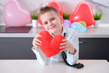 Charming, joyful, smiling boy with heart-shaped toy in his hands for Valentine's Day. Concept of...