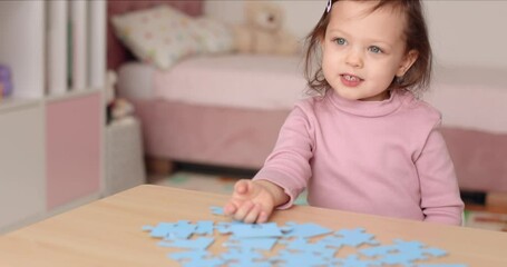 Cute little child girl connecting puzzle pieces on wooden desk in room, children development - Powered by Adobe