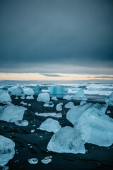 Scattered glacial ice on Diamond Beach under a moody sky, South Iceland...