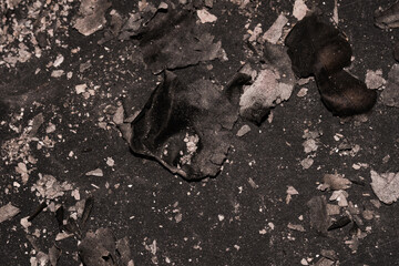 Scattered burnt ashes and debris on a dark background