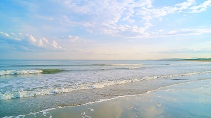 Obraz premium A beautiful beach with clear blue water and white foam from the waves. The sky is partly cloudy, creating a serene atmosphere.