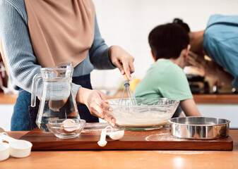 Happy Muslim family enjoying a fun baking session in the kitchen, parents teaching their kids how to make sweet treats, celebrating love, parenting, and childhood joy