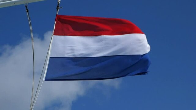 Dutch flag on ship flying in stormy winds.