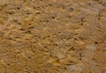 Ancient pale coloured stone background with a rough and pitted surface