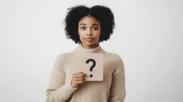 Young Black woman in minimalist beige sweater holds a question mark sign against a light background