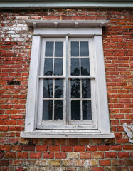 A dilapidated wooden and brick wall with a weathered, multi-colored appearance and an old window frame, creating a visually interesting and textured architectural scene.