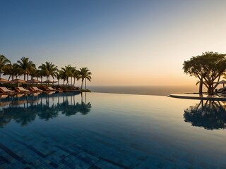Photograph of a Peaceful Resort Pool with Sunset Glow and a Beautiful Ocean Horizon