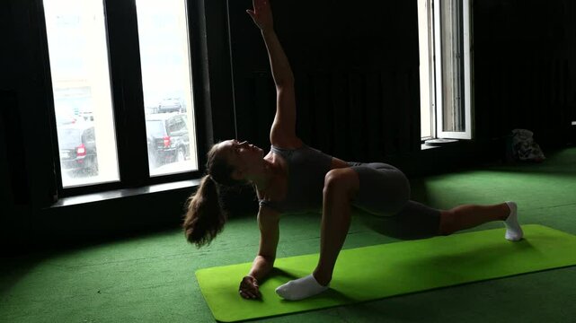 A woman performs yoga and stretches in a gym, promoting fitness