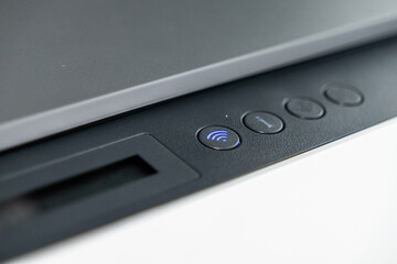 close-up of illuminated wi-fi button on modern printer control panel with minimalistic design
