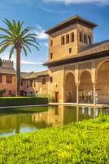 Obraz premium The Partal Palace in the Alhambra complex, Granada, Andalusia, Spain. Serene courtyard with reflecting pool, traditional architecture, and lush greenery.