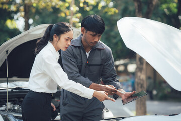 Car Trouble:  A concerned woman  points to the open hood of her car while a  mechanic attentively listens and explains the problem.  This image embodies a sense of trust and understanding.