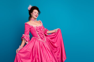 Charming young woman in a vibrant pink corset dress posing with elegance against a blue background