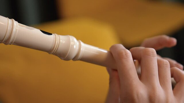 Skilled musician demonstrating precise finger positioning and embouchure technique while playing recorder flute against clean white background, capturing detailed hand movements