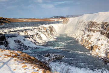 Beautiful waterfall of the Gullfoss falls. Photo taken in Iceland during a snow covered cloudy day 