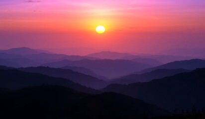Fototapeta premium Vibrant sunset paints the sky with purple hues and an orange glow, silhouetting mountains in a panoramic, ethereal landscape. A breathtaking twilight scene of nature's serene beauty.