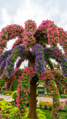 Decorative flowerpots in form of palm tree made of pink and purple petunia flowers in miracle garden in Dubai, United Arab Emirates. Vertical image