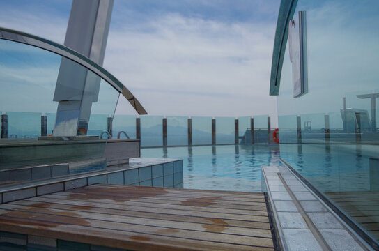 Outdoor infinity swimming pool onboard modern luxury cruiseship cruise ship liner with turquoise water under summer cloud sky