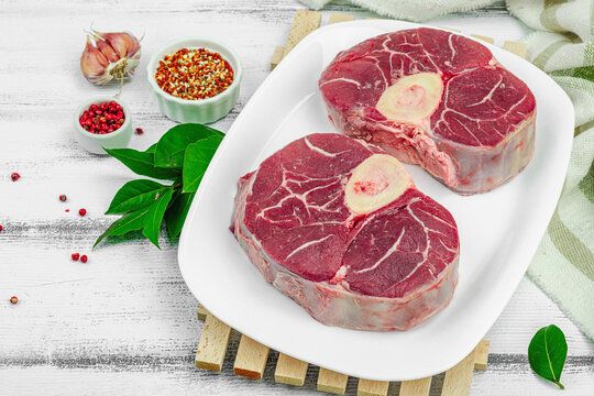 Raw ossobuco beef meat with spices and fresh herbs. Veal shank steak, traditional Italian ingredient - Powered by Adobe