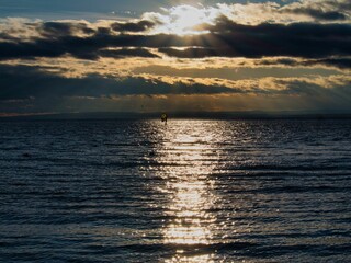 Sunset ocean with windsurfer silhouette.