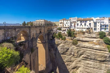 The Puente Nuevo bridge in El Tajo gorge in Ronda town in Spain. Ancient stone bridge spanning a deep gorge, overlooking a picturesque town nestled on a cliffside. Sunny day.