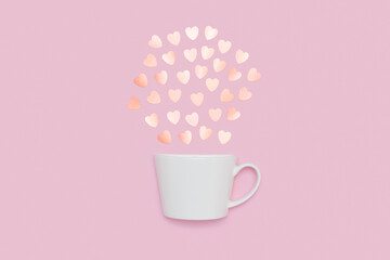 Creative minimalist composition of a white coffee cup spilling pastel heart-shaped confetti, set against a pink background, symbolizing love and warmth.