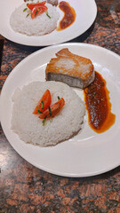 Two plates of home cooked tuna steak served with steamed rice, tomato garnish, and sauce showing togetherness 