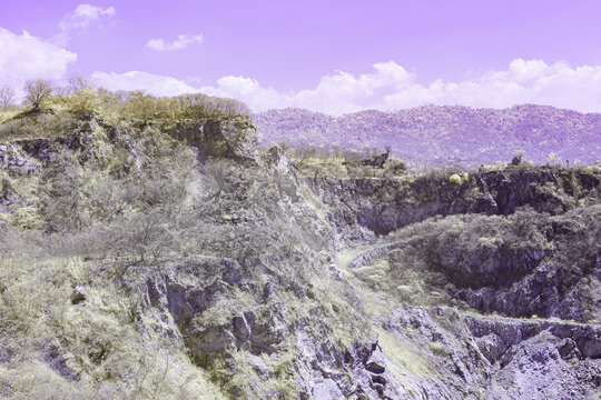 Infrared photography, a rocky landscape with steep cliffs and a backdrop of distant mountains - Powered by Adobe