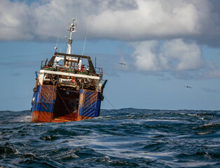 Large fishing vessel hauls trawling gear in the Atlantic waters.