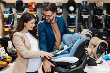 Attractive middle age couple enjoying in buying baby stroller and car seat. Heterosexual couple in...