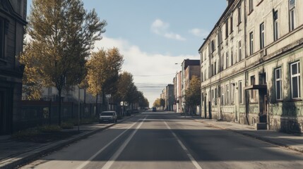 Obraz premium Abandoned street scene with autumn trees lining the road and old buildings under a cloudy sky