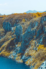 Obraz premium Infrared photography, a landscape with a body of water at the bottom and a rocky cliff. The cliff has vegetation with autumn-colored trees