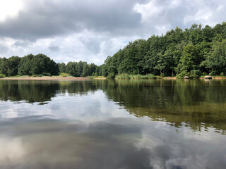 river, forest on the bank dark low clouds reflection , summer green landscape