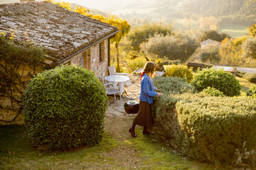 A woman enjoying a serene moment in a rustic garden, surrounded by lush greenery and a charming...