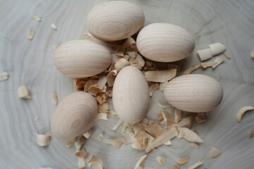 Close-up of wooden eggs with wood shavings on a light surface, highlighting natural textures, craftsmanship, and rustic aesthetics, perfect for themes of handmade crafts, woodworking, or minimal desig