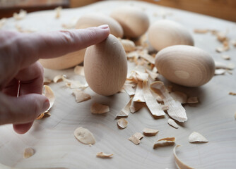 Close-up of wooden eggs with wood shavings on a light surface, highlighting natural textures,...
