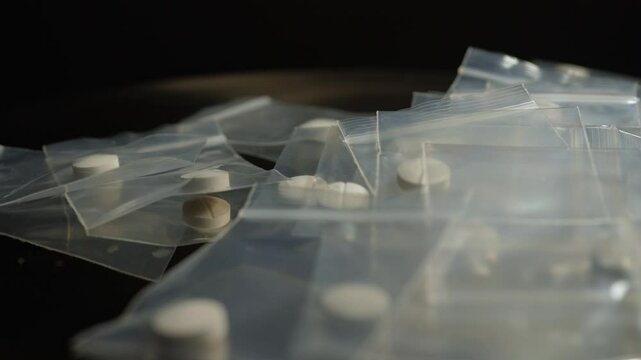 Powder pressed Fentanyl and opioid mixed pills packed in small bags for sale on the streets, scattered on the table of drug dealer. Opioid epidemic and major public health crisis.