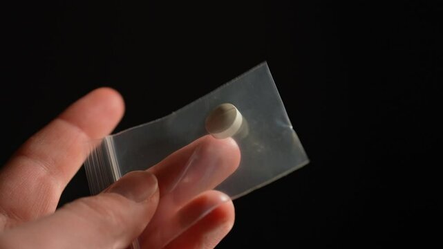 Drugs addicted person just purchased illegal Heroin or Fentanyl like powder substance from the dealer on the street and looking at it. Person ready to have a party. Illegal street drugs epidemic.