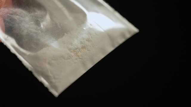 Drugs addicted person just purchased illegal Heroin or Fentanyl like powder substance from the dealer on the street and looking at it. Person ready to have a party. Illegal street drugs epidemic.